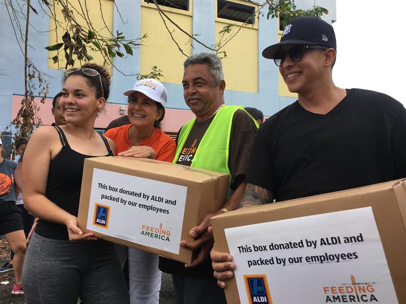 El cantante urbano Daddy Yankee (d) e integrantes del Banco de Alimentos de Puerto Rico entregan cajas de comida a ciudadanos afectados por el huracán María