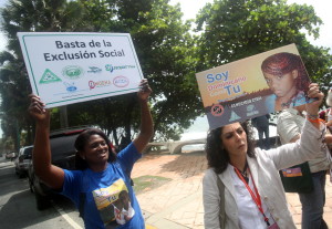 Una joven del "Movimiento Reconocido" (i) acompa&ntilde;ada de una dirigente feminista mexicana se manifiestan a las afueras del lugar donde se lleva a cabo la XII Conferencia Regional sobre la Mujer de Am&eacute;rica Latina y el Caribe, para protestar por una sentencia que niega la nacionalidad a descendientes de haitianos .