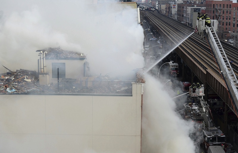 Varios bomberos trabajan en la extinción de un incendio declarado en un edificio del barrio de Harlem, Nueva York.