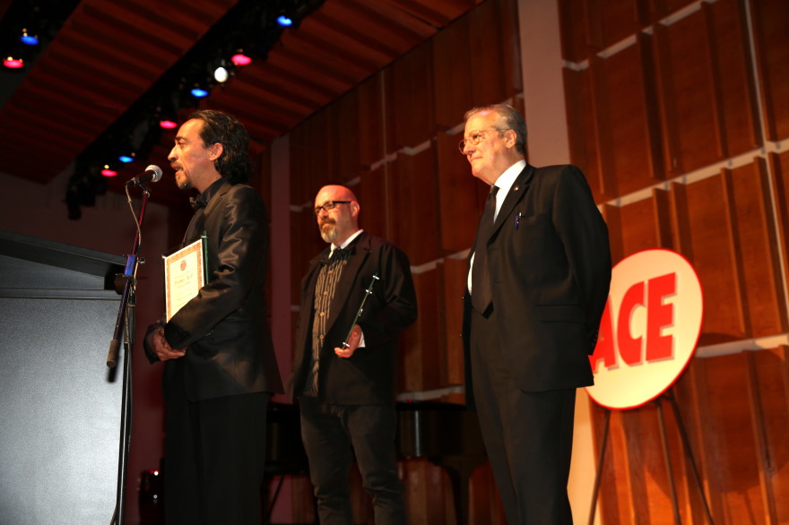 Roberto Sosa, frente al micrófono, luego de que él y Sebastián del Amo recibieran premios por la película mexicana “El Fantástico Mundo de Juan Orol. Con ellos, Manolo García-Oliva, presidente emérito de la ACE.