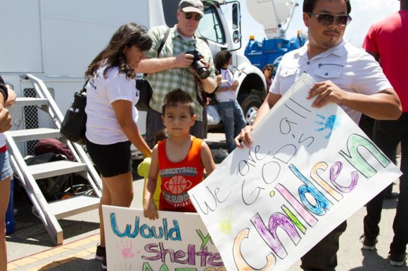 Un grupo de personas sostiene un letrero que dice: "Todos somos hijos de Dios" durante una manifestaci&oacute;n frente al Centro de Procesamiento de La Patrulla Fronteriza en Murrieta, California.