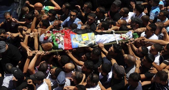 Un grupo de palestinos porta el cad&aacute;ver del joven Mohamed Al -Araj, de 17 a&ntilde;os, durante su funeral en el campo de refugiados de Qalandia, crca de la ciudad cisjordana de Ramala.
