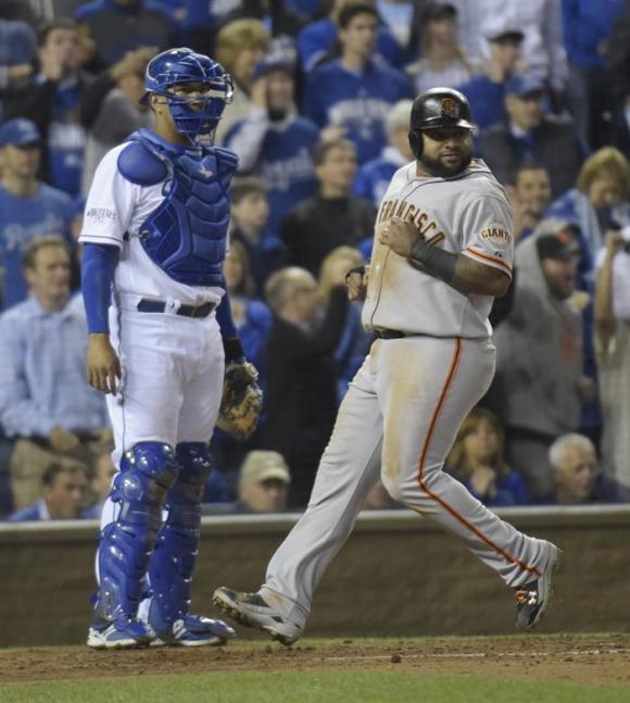 El jugador de Gigantes Pablo Sandoval (d) anota una carrera ante el receptor de Reales Salvador P&eacute;rez.