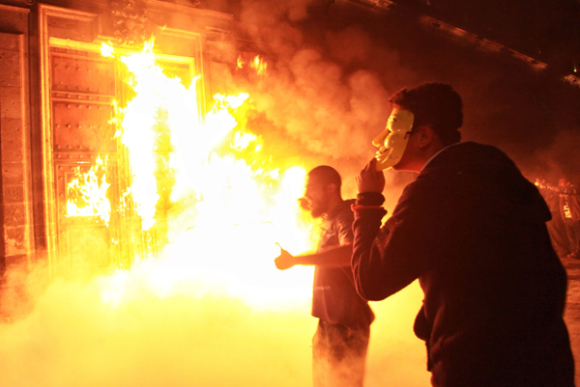 Una veintena de manifestantes escapuchados derribaron ayer las vallas de seguridad de los alrededores del Palacio Nacional, sede del Ejecutivo mexicano, y prendieron fuego a la puerta principal del hist&oacute;rico edificio. 