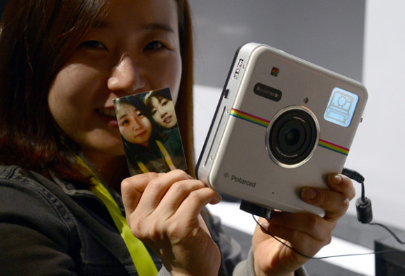Una mujer muestra una impresi&oacute;n de la c&aacute;mara instant&aacute;nea Polaroid Socialmatic.