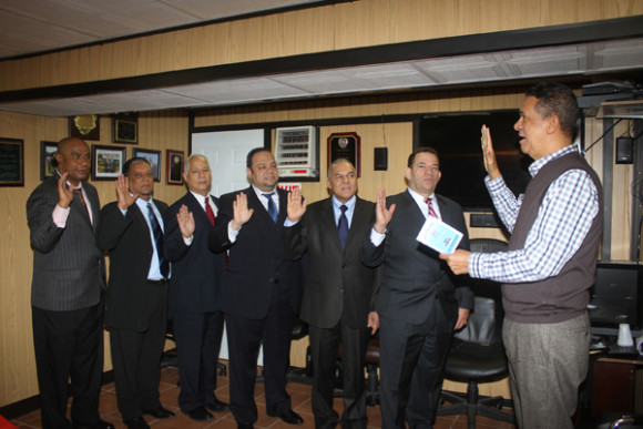 Tom&aacute;s Gloss, (der.), juramenta a los nuevos integrantes directivos de la base Riverside Car & Limo Service. Ellos son: Elvin Marte, (#148), presidente; Francisco Solano (#211), vicepresidente; Angel de la Rosa, (#297), tesorero; Digno Hidalgo, (#193), secretario; Mateo Breton, (#160), disciplina; Andr&eacute;s Mej&iacute;a, (#243), director vocal y V&iacute;ctor Encarnaci&oacute;n, (#00), auditor interno, quien no aparece en la foto.  