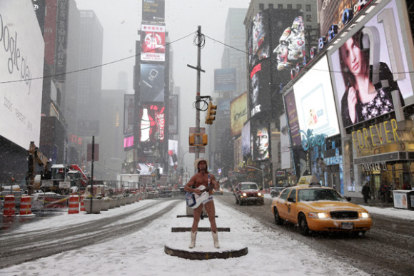 El artista callejero Robert John Burck, conocido como "El Vaquero Desnudo", canta en Times Square.