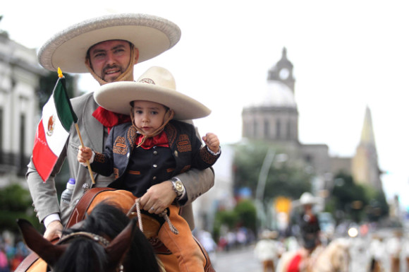Un charro pasea orgulloso con su hijo a la grupa de su caballo en Guadalajara. 