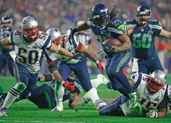 Marshawn Lynch (C) de los Seahawks de Seattle se escapa de Vince Wilfork (d) y Rob Ninkovich (i) durante la segunda mitad del partido del Super Bowl XLIX.