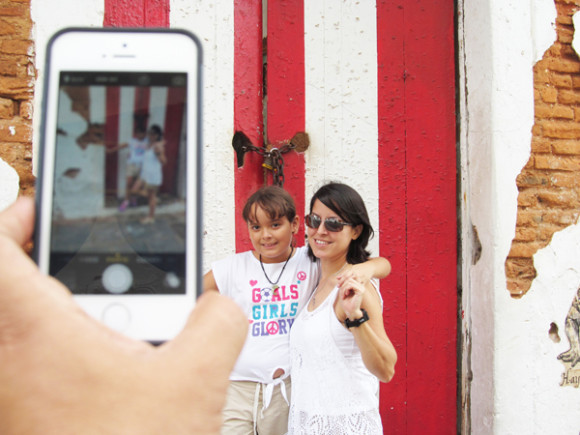 Anyeliz Rosado se fotografía junto a su hija ante la puerta donde está pintada la bandera puertorriqueña.