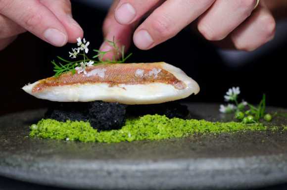 Mero (pescado chileno) preparado en horno de barro (tierra) con papa bruja y flores, elaborado por el Chef Rodolfo Guzmán del restaurante Boragó de Santiago de Chile.