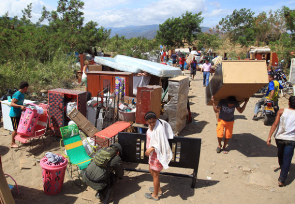 Cientos de colombianos cargan sus pertenencias por el río Táchira desde Venezuela hacia el sector La Parada, Colombia.