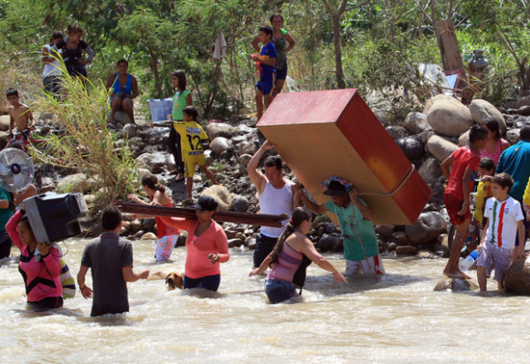 Cientos de colombianos cargan sus pertenencias por el río Táchira desde Venezuela hacia el sector La Parada, Colombia.