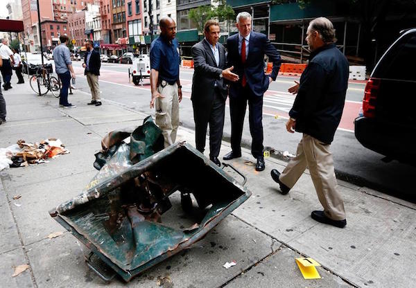 Alcalde de Nueva York, Bill de Blasio (2-R) y el gobernador de Nueva York, Andrew Cuomo (3-R) y los agentes de polic&iacute;a no identificados se paran frente a un contenedor de basura destrozado mientras recorre el sitio de una explosi&oacute;n que se produjo durante la noche en el barrio de Chelsea de Nueva York .
