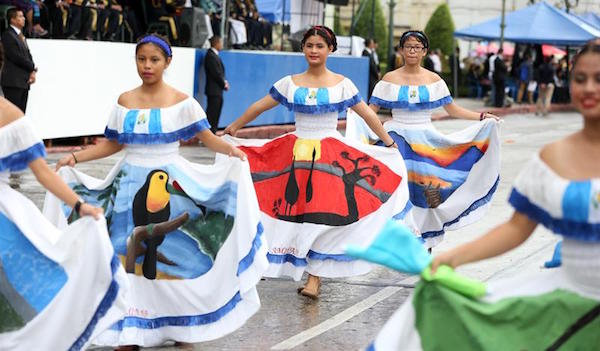 Estudiantes con vestidos adornados con estampas de paisajes de Guatemala participan en un desfile por el 195 aniversario de la independencia de Guatemala.