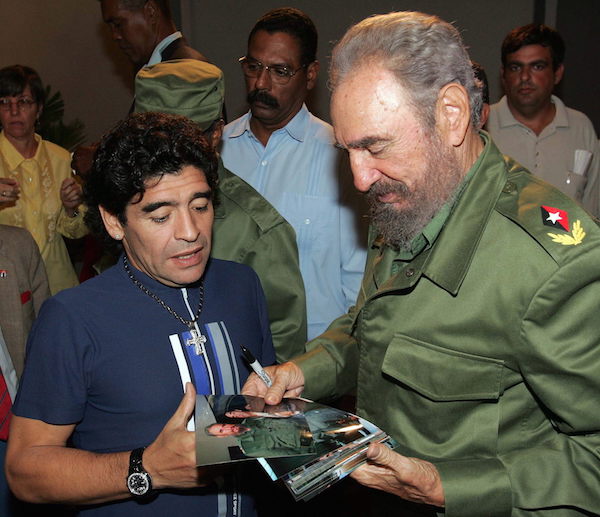 El ex futbolista argentino Diego Armando Maradona (izq) y el presidente cubano Fidel Castro (der) observan varias fotos donde aparecen juntos, despuÈs de comparecer en el programa televisivo ìMesa Redondaî en La Habana.