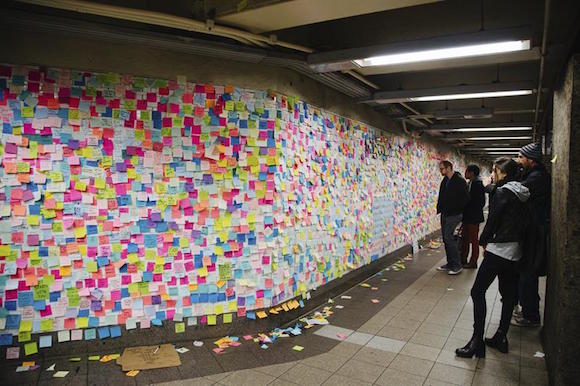 Varios ciudadanos observan las notitas de colores que cubren un muro y que forman parte de la pieza artística "Subway Therapy" en la estación de metro de Union Square en Manhattan, Nueva York.