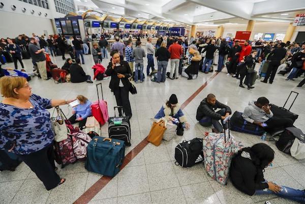 Pasajeros varados en el aeropuerto de Atlanta (Georgia) habla por tel&eacute;fono o descansan en el suelo este pasado domingo. La compa&ntilde;&iacute;a a&eacute;rea Delta se vio hoy obligada a cancelar otro centenar de vuelos por culpa del apag&oacute;n inform&aacute;tico que sufri&oacute; este domingo y pidi&oacute; disculpas a los pasajeros afectados. EFE