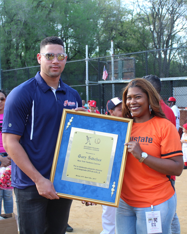Thania Salazar de Allstate, entrega placa de reconocimiento en nombre de la Lia Paulino a Gary Sánchez, catcher de los Yankees de Nueva York.