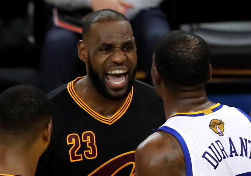 El jugador Golden State Warriors Kevin Durant (d) y el jugador de Cleveland Cavaliers LeBron James (i) intercambian palabras en la cancha, en la segunda mitad del partido cinco del juego de baloncesto de la NBA en el Oracle Arena de Oakland, California.