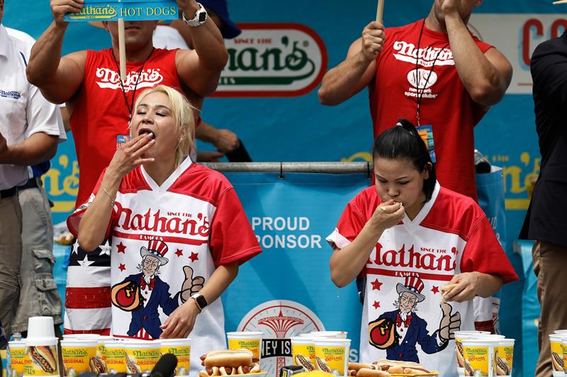 Las competidoras Miki Sudo (i) y Sonya Thomas (d) comen perritos calientes durante el Concurso anual femenino de perritos calientes de Nathan, celebrado en Coney Island, Nueva York