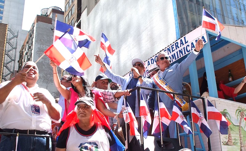El cónsul Carlos A. Castillo mientras saludaba desde la carroza del Consulado Dominicano a espectadores, y el merenguero Rubby Pérez los deleitaba.
