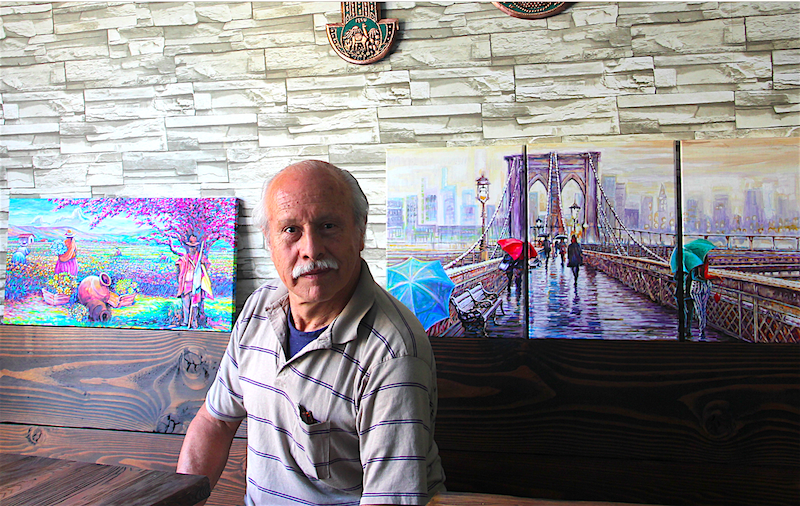 Jaime Obando con otras dos obras suyas, un paisaje andino y una pintura del Brooklyn Bridge, que son parte de la colección pictórica de The Inkan.