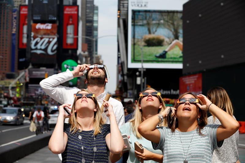Un grupo de personas miran el eclipse solar hoy, lunes 21 de agosto de 2017, desde el Times Square, en Nueva York