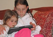 Niños bilingües Dos hermanas leyendo un cuentacuentos en su tableta en idioma inglés.