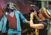 Una seguidora del cantante jamaicano Bob Marley, fotografía un póster del artista en Kingston (Jamaica).