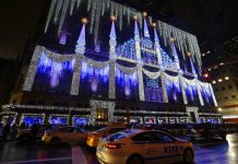 Fotografía de la tienda por departamentos Saks Fifth Avenue iluminada frente al árbol de Navidad Rockefeller Center.