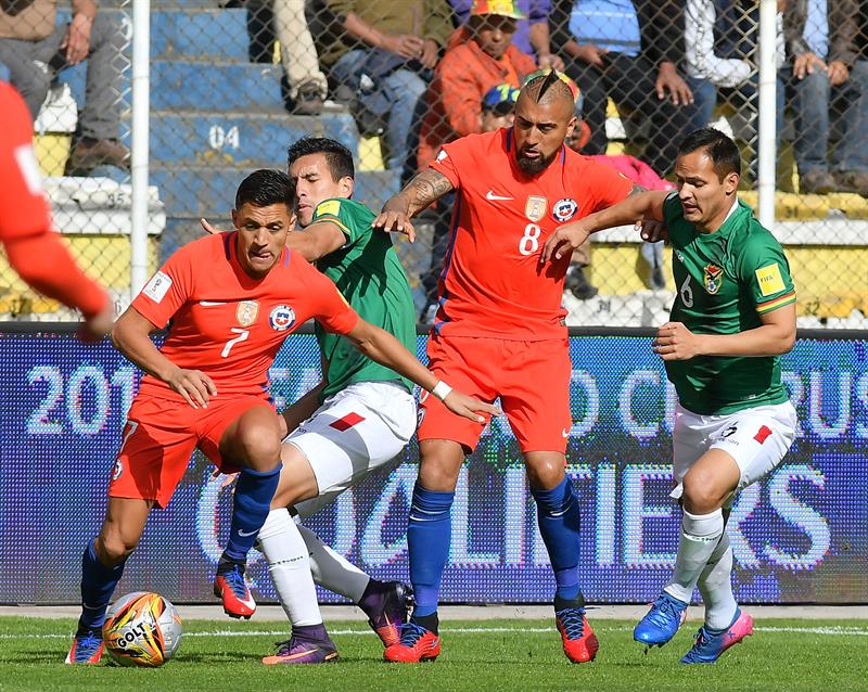 El boliviano Leonel Justiniano (d) disputa el balón con los chilenos Arturo Vidal (c) y Alexis Sánchez (i) durante el partido entre Bolivia y Chile por las eliminatorias al Mundial de Rusia 2018 que terminó 1-0 a favor de Bolivia