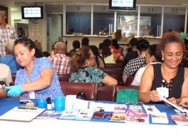 Contribuyentes que acuden en busca de servicios en el Consulado General de la República Dominicana en esta ciudad, mientras son atendidos sobre prueba de diabetes y reciben información sobre seguro médico.