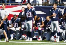 Los jugadores de New England Patriots se toman de las manos y se arrodillan durante el Himno Nacional antes del comienzo de su juego.
