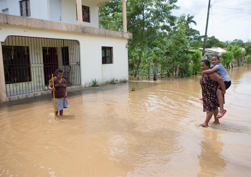 Varias personas caminan por una calle inundada hoy, viernes 22 de septiembre de 2017, tras el paso del huracán María en la ciudad de Nagua (República Dominicana).