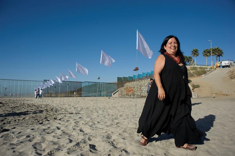 Betsabeé Romero quien camina cerca a su instalación artística llamada "Tu huella es el camino, tu bandera es de paz", compuesta por un centenar de banderas blancas colocadas en los lados del muro fronterizo para rendir tributo a inmigrantes con "espíritu de paz" que cruzan la frontera.