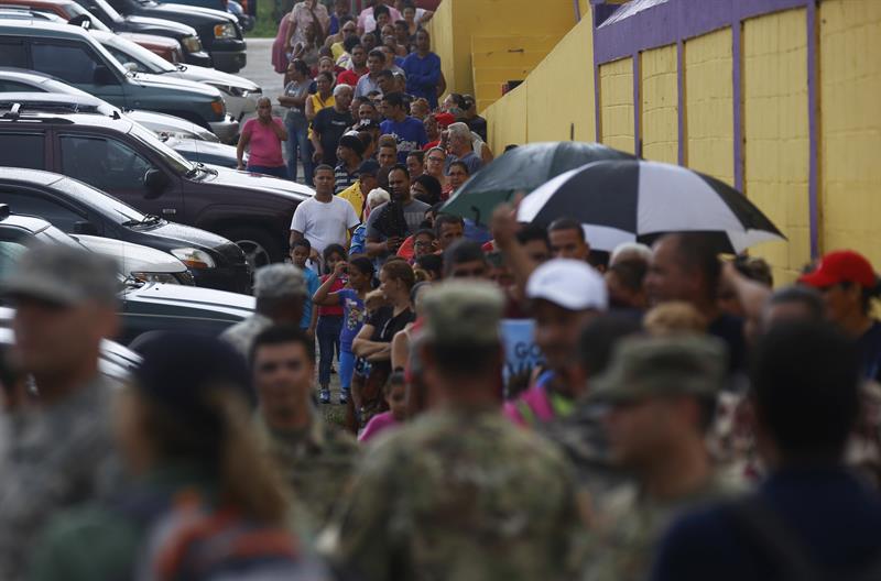 Personas damnificadas por el paso del huracán María hacen fila para recibir del ejército sus raciones de suministros.