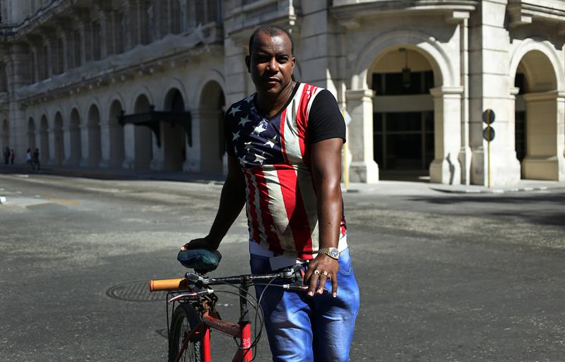 Un hombre vestido con la bandera de Estados Unidos camina con su bicicleta por una calle hoy, mi&eacute;rcoles 08 de noviembre de 2017, en La Habana 