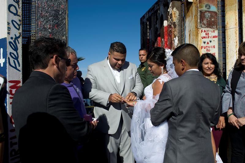 Brian Houston le pone un anillo a su prometida Evelia Reyes durante la celebración de su boda en una de las puertas de la valla fronteriza entre Estados Unidos y México.
