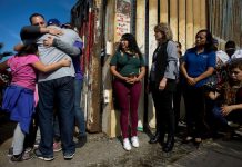 Un grupo de personas abrazan a sus familiares en una de las puertas de la valla fronteriza entre Estados Unidos y México