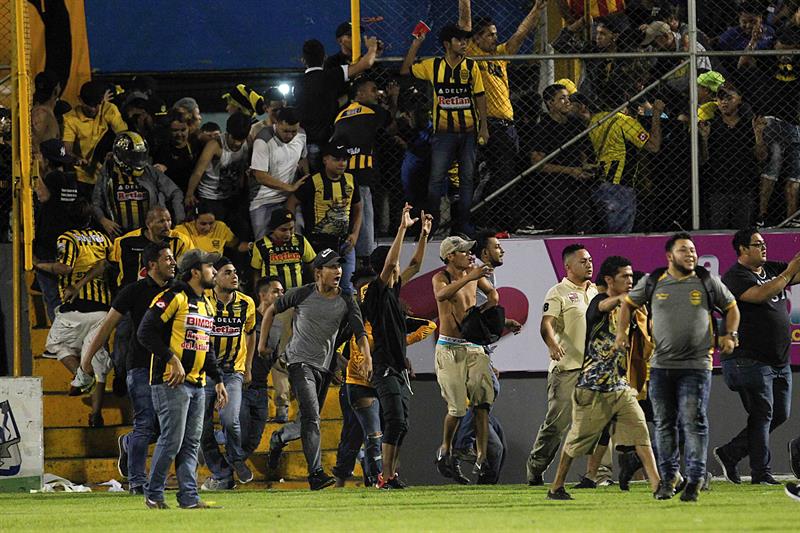 Mientras tanto, los ánimos se caldeaban en la grada sur del estadio, donde enardecidos aficionados del Marathón que sacudían un portón superaron este obstáculo y se metieron en la cancha.