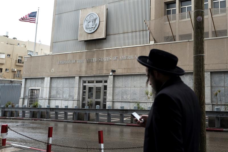 Un jud&iacute;o ultraortodoxo revisa su m&oacute;vil mientras pasa delante de la Embajada de Estados Unidos en Tel Aviv (Israel)