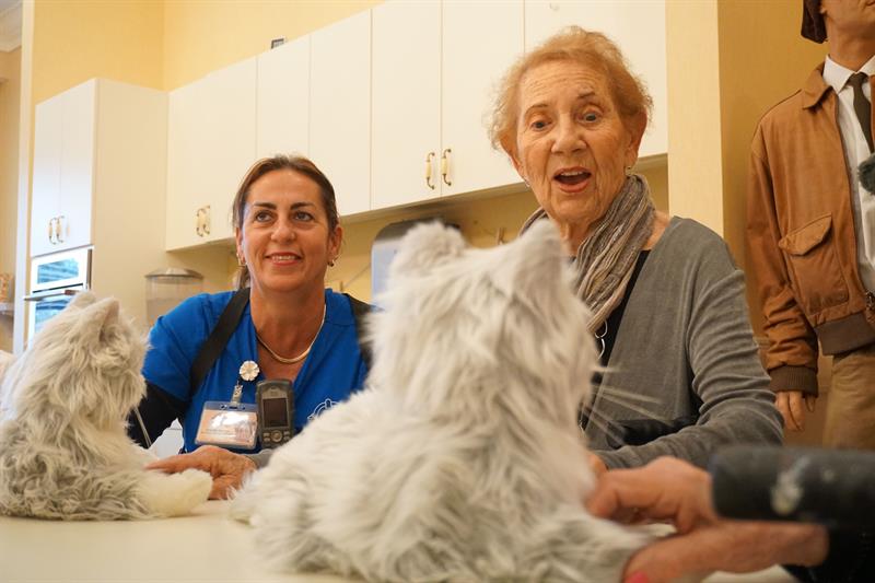 Una residente de Palace Gardens interactuando con un gato robot, en la sede del hogar en la ciudad de Homestead, sur de Florida.