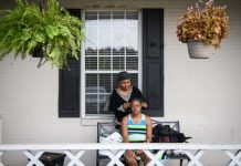 Jean Moore le pone una diadema a su hermana, Ruby Wilson, frente a The Magnolia, la instalación de vida asistida donde vive Wilson. (Andrew Craft para Kaiser Health News)