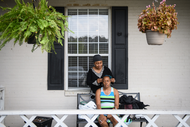 Jean Moore le pone una diadema a su hermana, Ruby Wilson, frente a The Magnolia, la instalación de vida asistida donde vive Wilson. (Andrew Craft para Kaiser Health News)