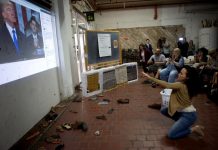 Personas arrojan zapatos a una proyección del presidente estadounidense Donald Trump durante su discurso sobre el Estado de la Unión