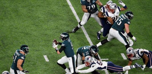 El mariscal de campo de los Philadelphia Eagles Nick Foles (C) se revuelve mientras el linebacker exterior de los New England Patriots Kyle Van Noy (R) persigue durante el Super Bowl LII en el US Bank Stadium en Minneapolis, Minnesota