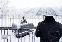 Un hombre observa a un agente de los servicios secretos que vigila el complejo de la Casa Blanca durante una intensa nevada