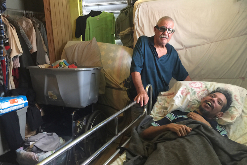 Osvaldo Mart&iacute;nez (izq.) cuida a su hijo, Osvaldo Daniel Mart&iacute;nez, quien sufre una discapacidad progresiva y tiene Medicaid. Con pocos neur&oacute;logos en la isla, el joven todav&iacute;a no ha podido ver a un especialista para tener un diagn&oacute;stico oficial. (Sarah Varney/KHN)