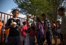 Migrantes centroamericanos esperan en fila por alimento durante su paso por México.